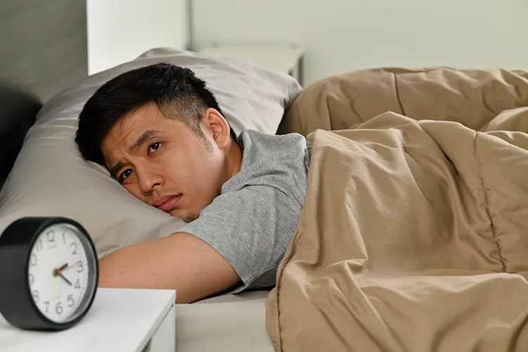 一位民眾因睡眠不足而難以入睡、躺在床上的示意插圖,象徵失眠可能影響全身健康